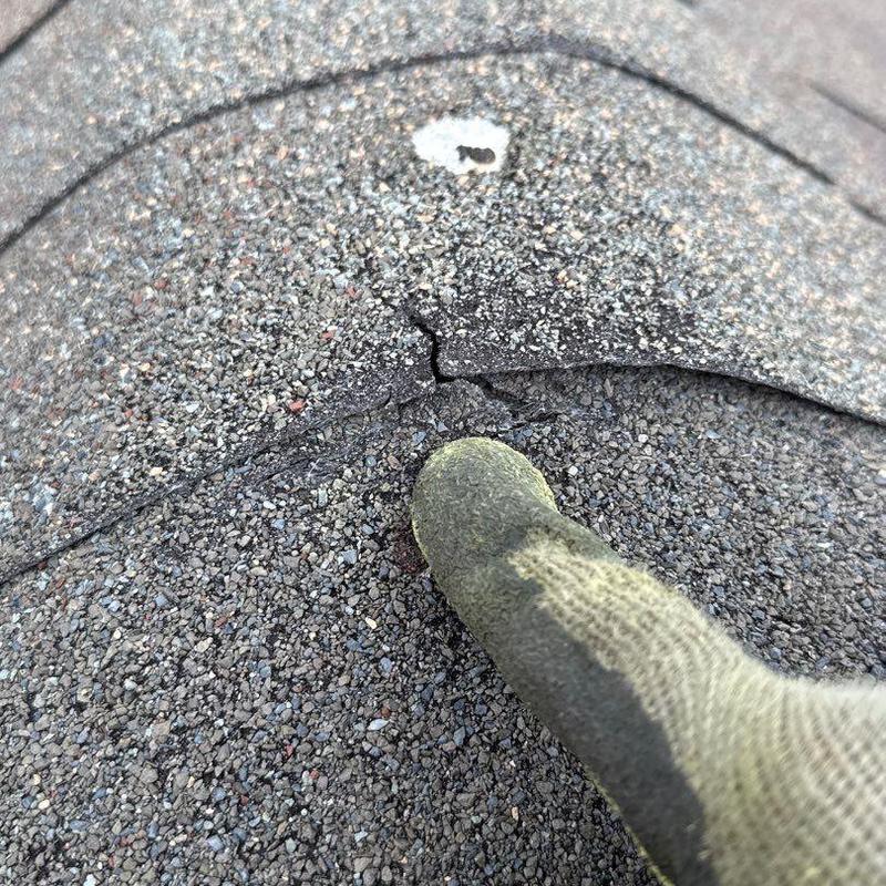 Asphalt shingle crack with nail rust and glove finger