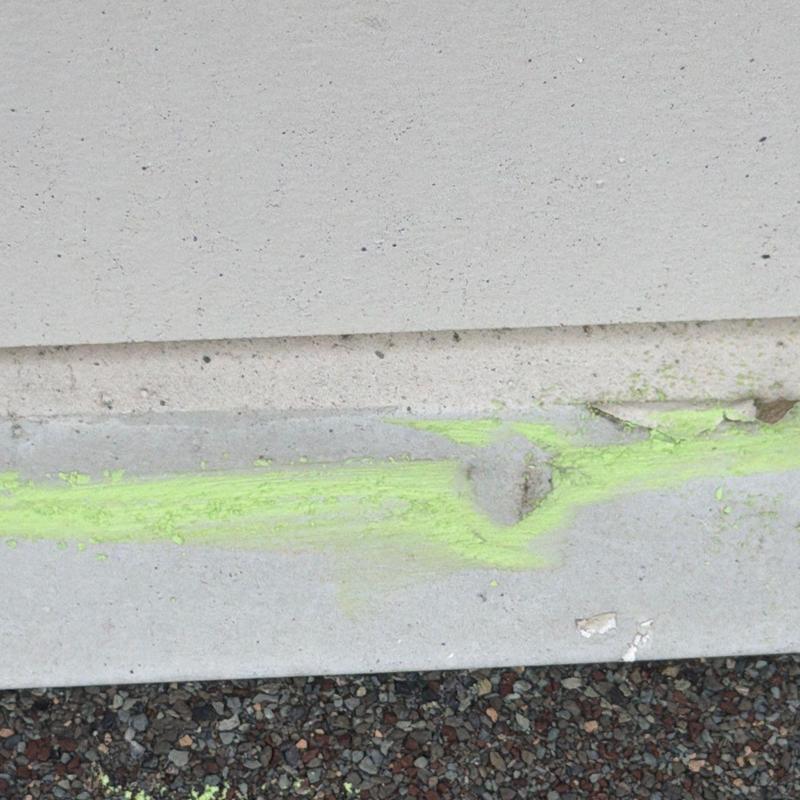 Concrete foundation with yellow chalk marking damage