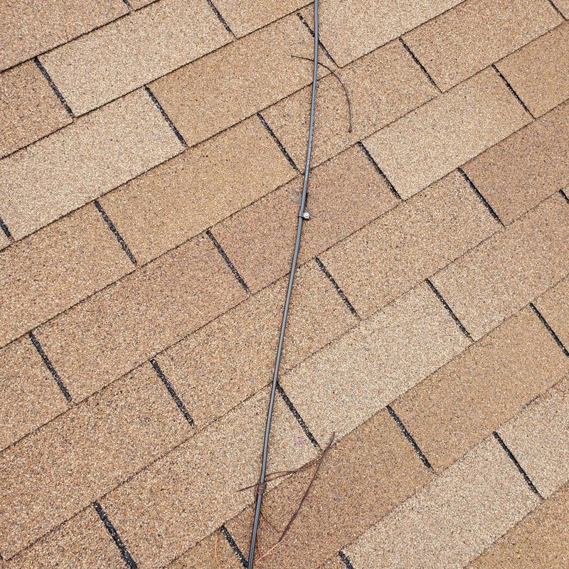 Roof shingles with hail damage near cable attachment