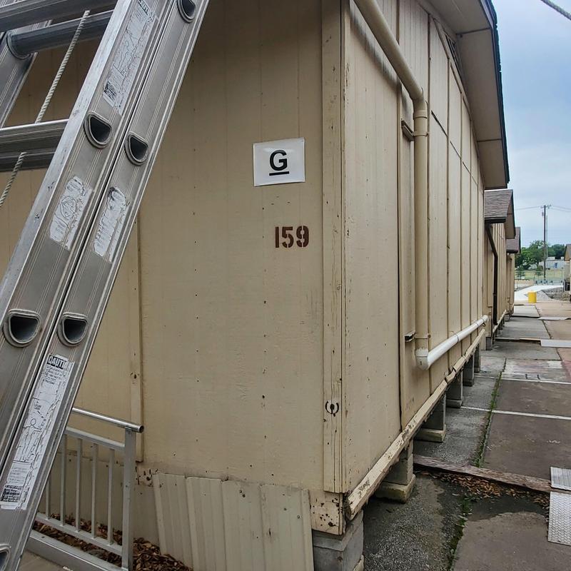 Exterior wall paneling and piping with ladder nearby