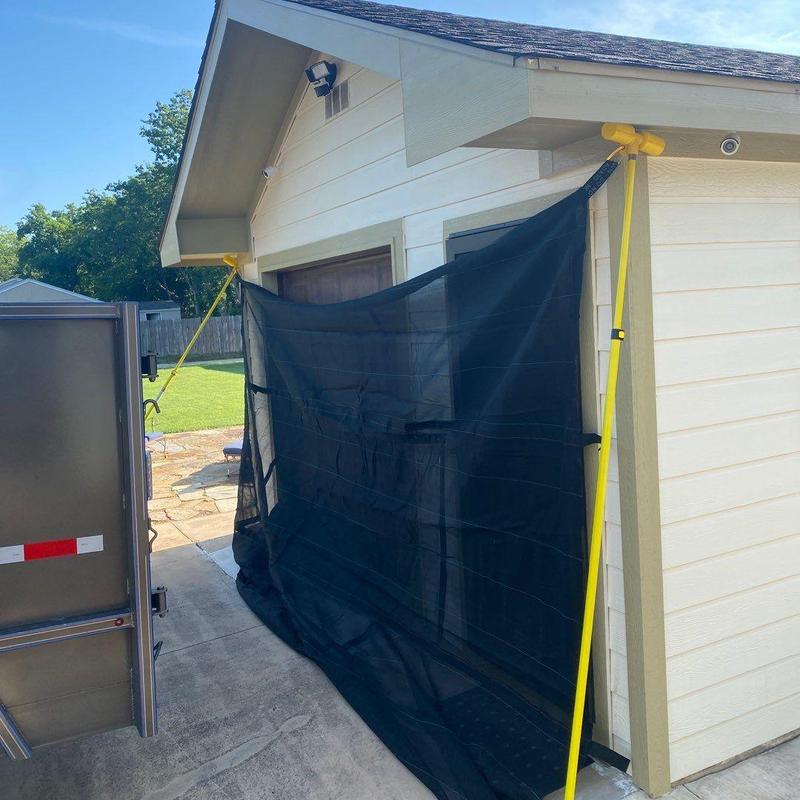 Roofing debris containment netting on house exterior Roofing debris containment netting on house exterior