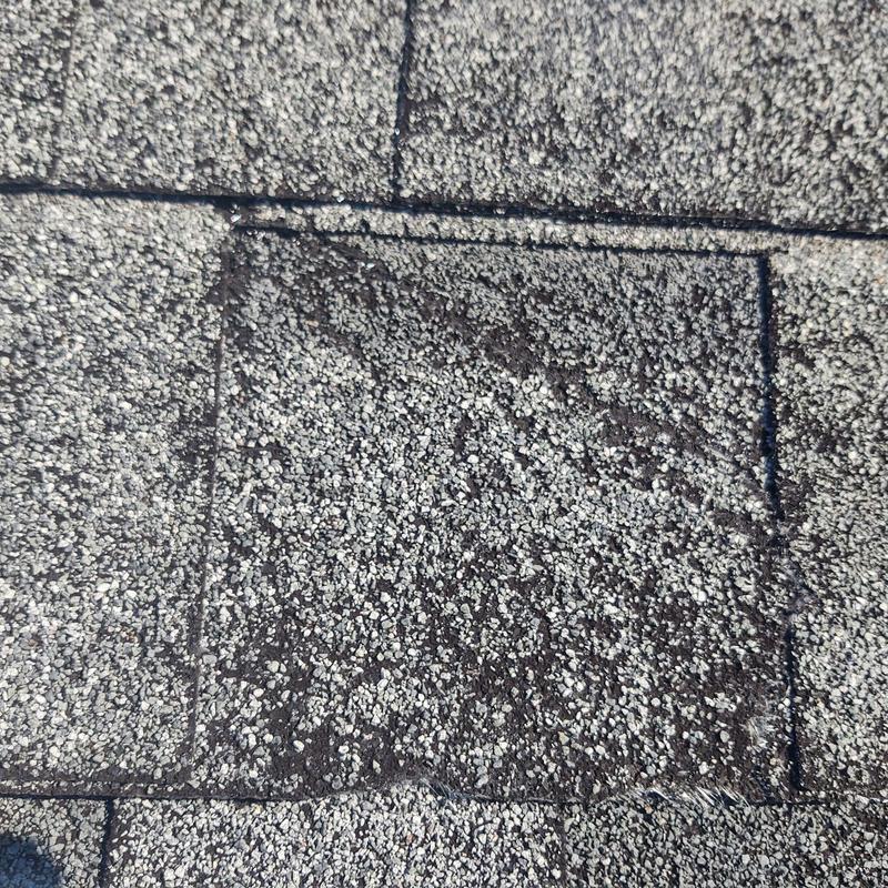 Brittle asphalt shingle with creased damage close-up