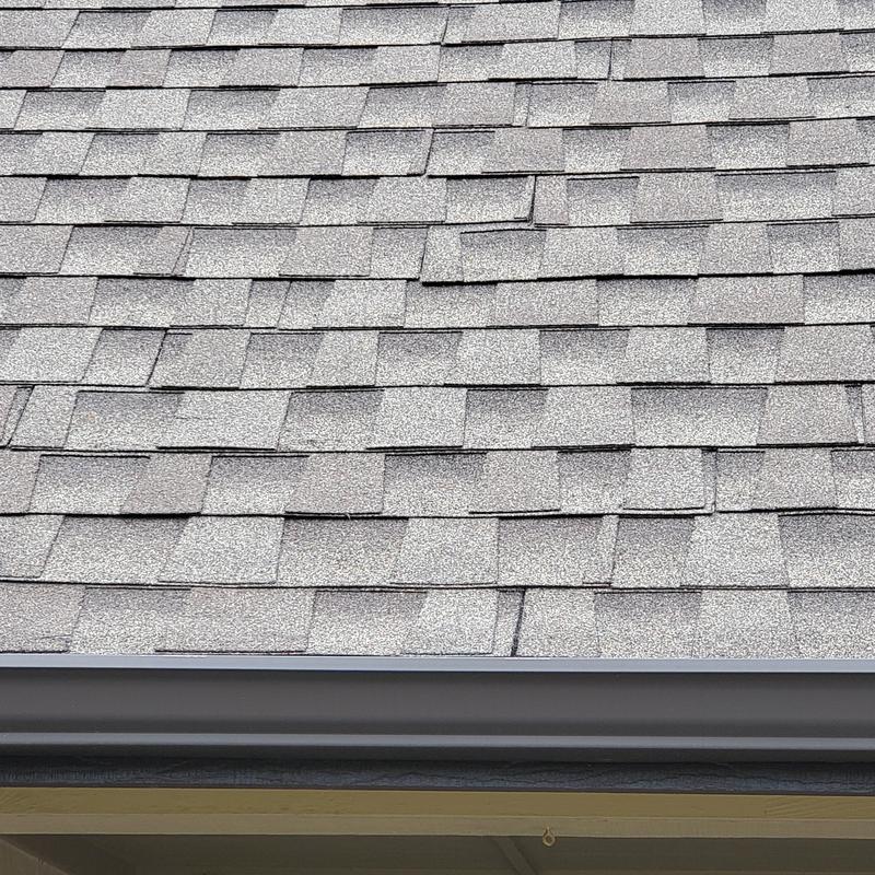 Asphalt roof shingles with hail storm damage near gutter