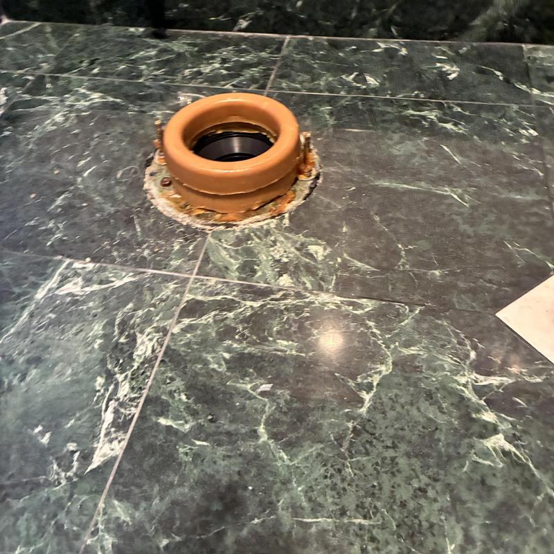 Toilet flange on green marble tiled floor installation site