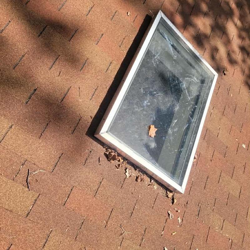 Skylight flashing on shingle roof with leaf debris