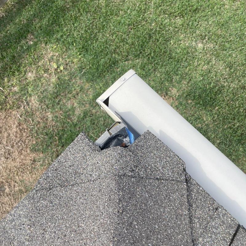 Asphalt shingle roof edge with minor damage near gutter