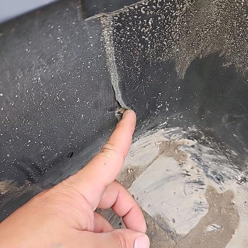 Flat roof membrane with damaged seam and finger pointing Flat roof membrane with damaged seam and finger pointing