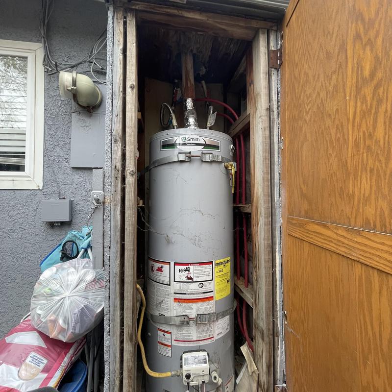 Water heater unit in wooden closet with piping