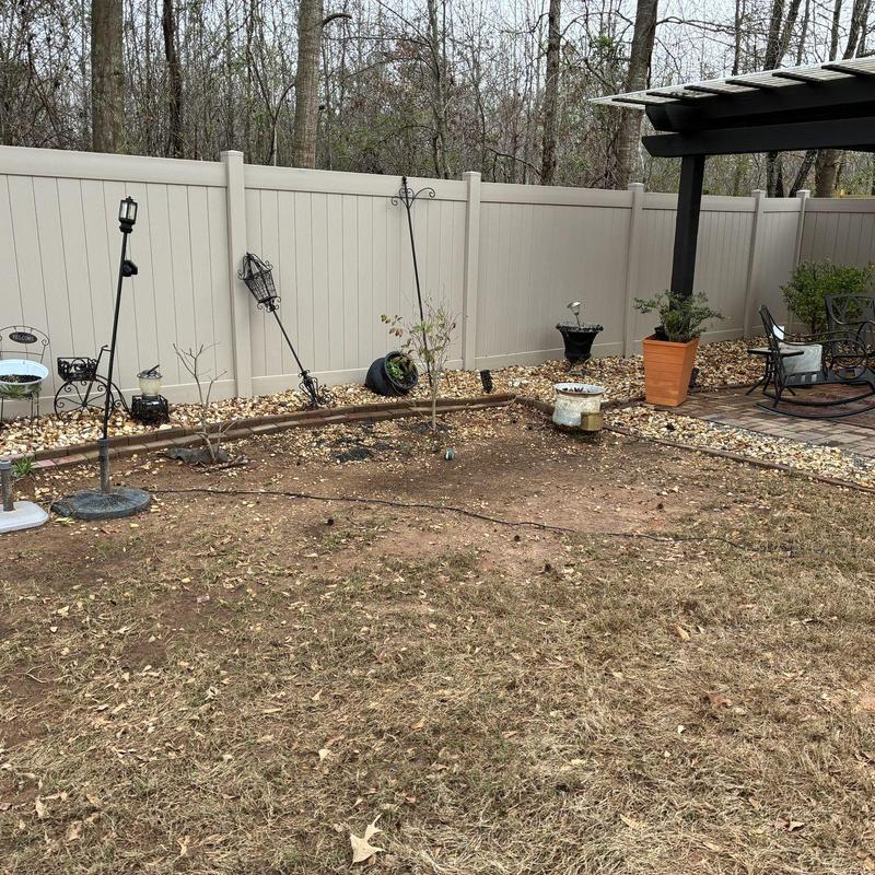 Beige vinyl privacy fence with gate and landscaping