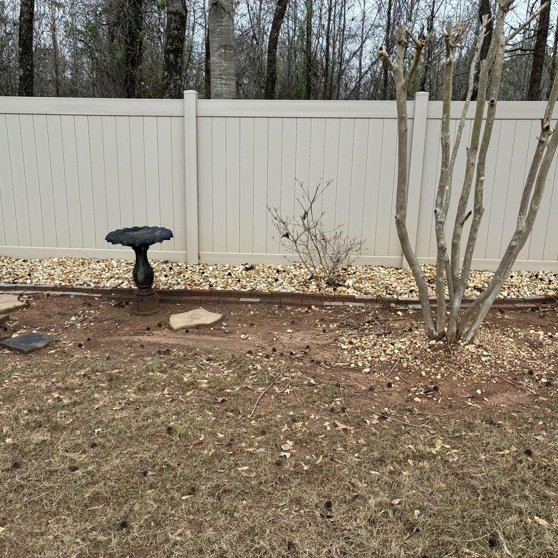 Beige vinyl privacy fence with landscaping rocks
