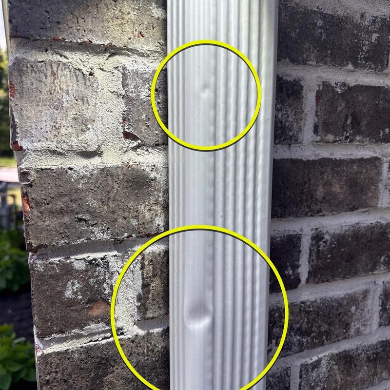 Metal downspout with hail dents marked