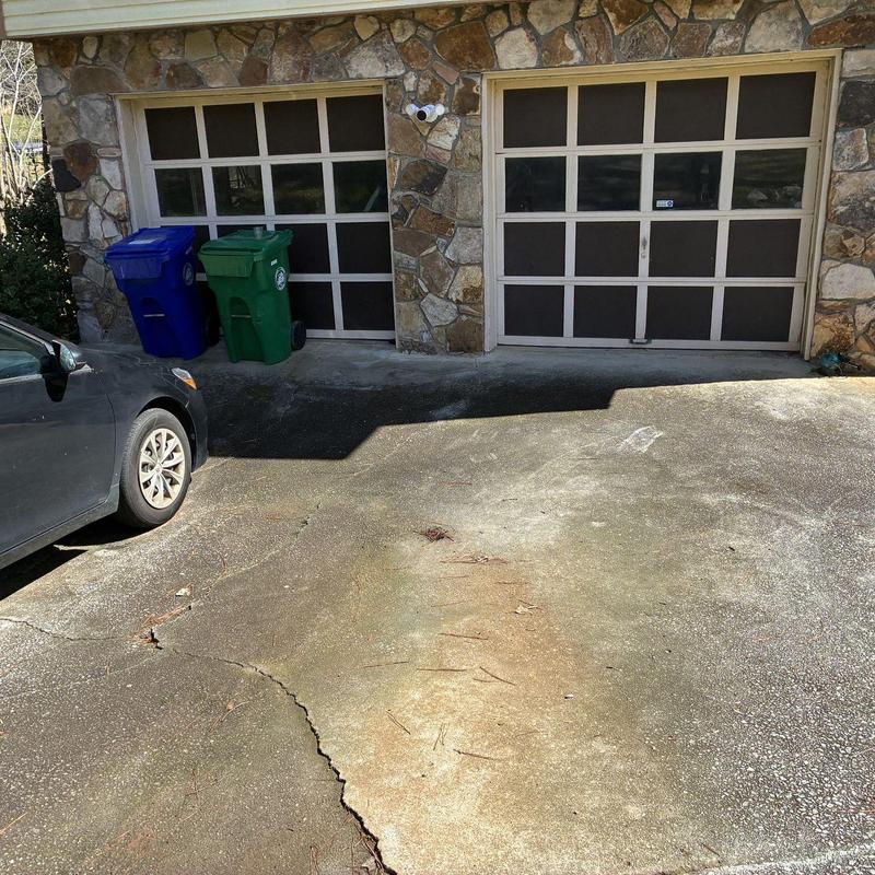 Concrete driveway cracks and surface wear near garage doors