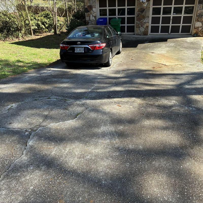 Concrete driveway with cracks and surface wear near garage