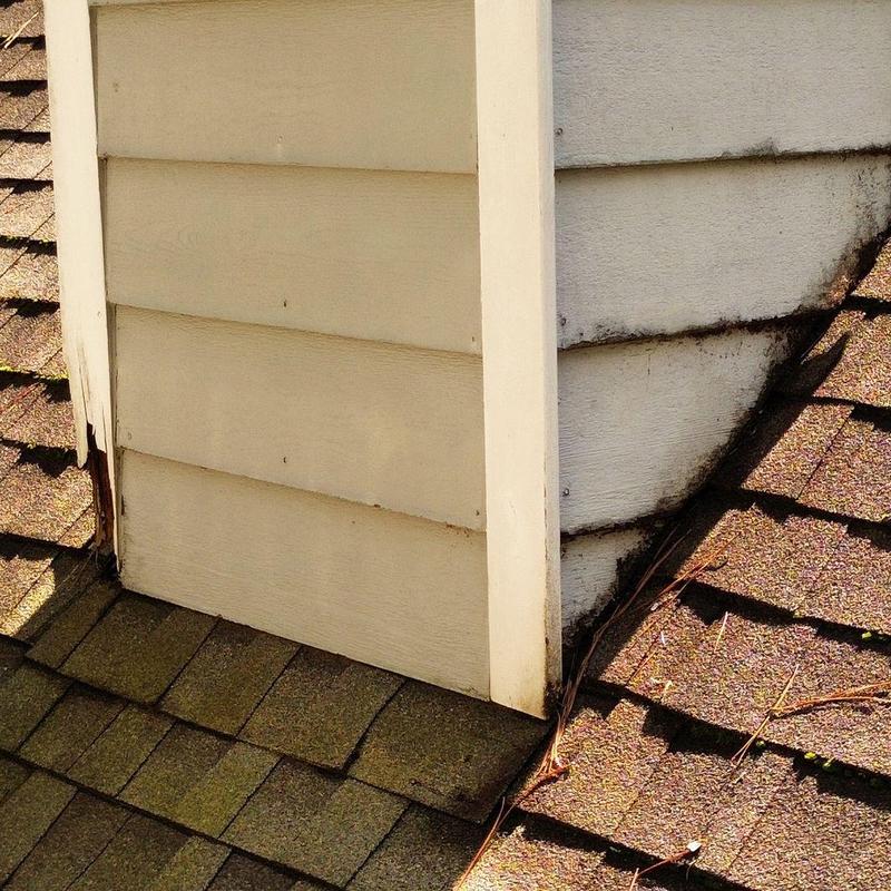 Chimney siding and roof shingle damage near base