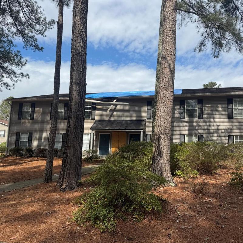 Apartment building roof with blue tarp after tree damage
