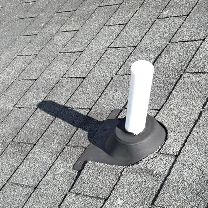 Roof pipe boot with aged rubber flashing on slate shingles