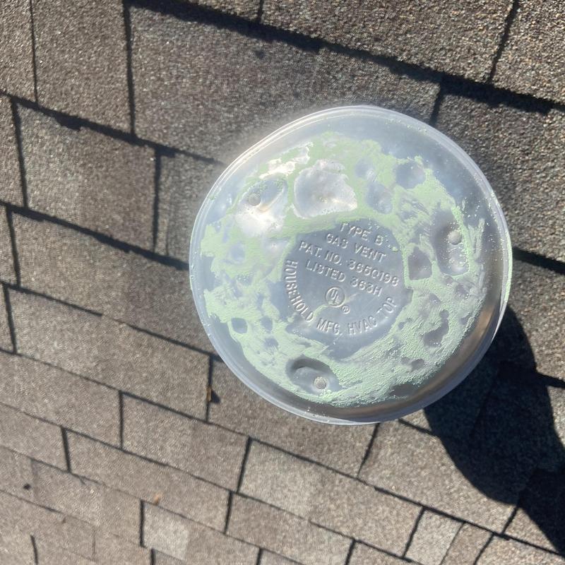 Gas vent cap on shingled roof with powder residue