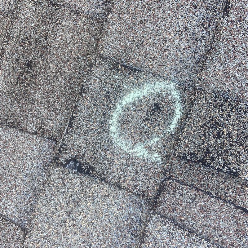 Asphalt roof shingle with storm damage marked with chalk