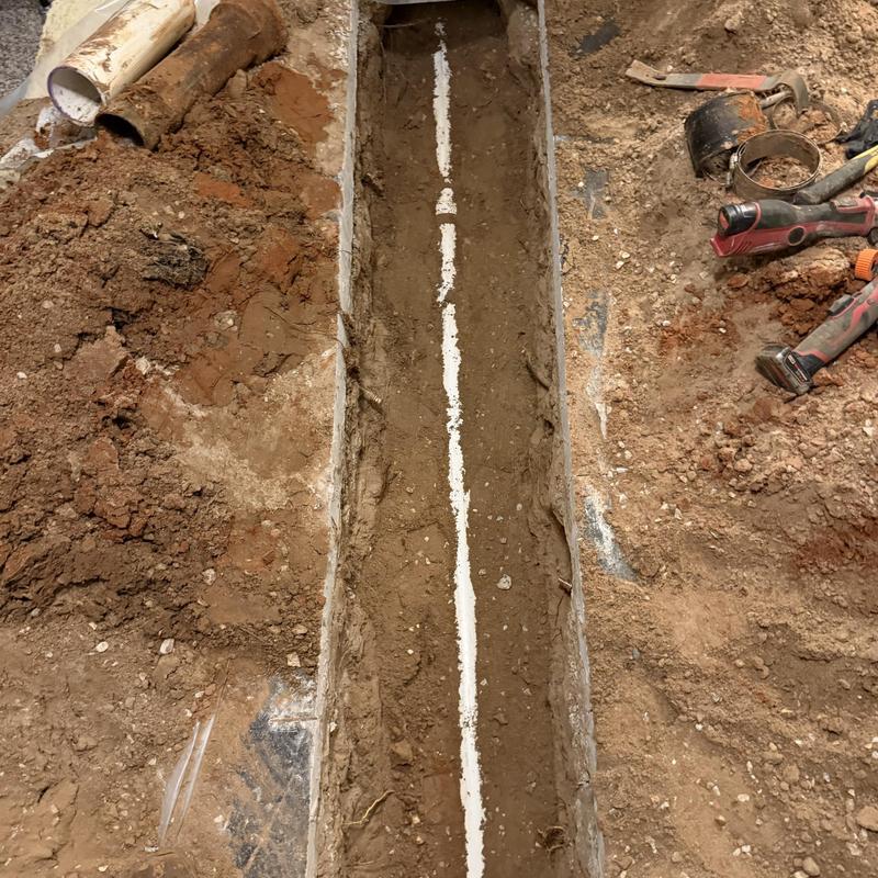 Sewer pipe trench excavation in slab home