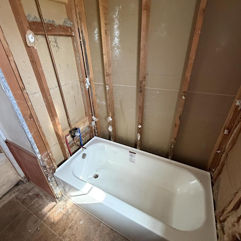 New bathtub installation with exposed plumbing walls