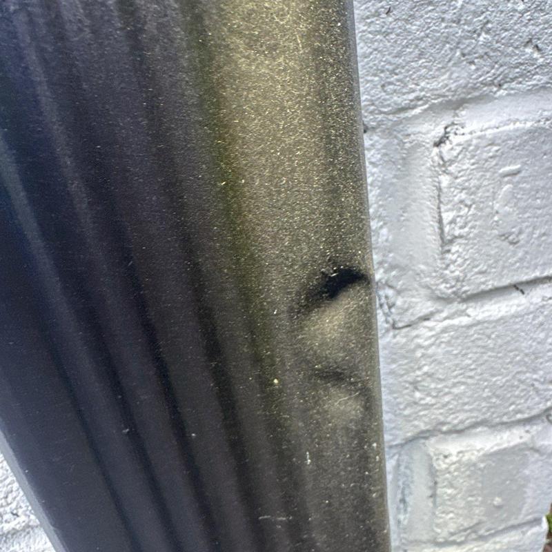 Metal downspout dent from hail damage close-up