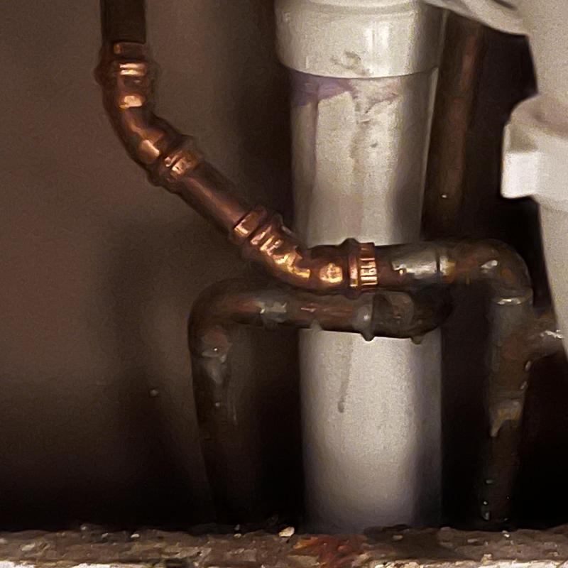 Copper water supply pipes with fittings near drain pipe