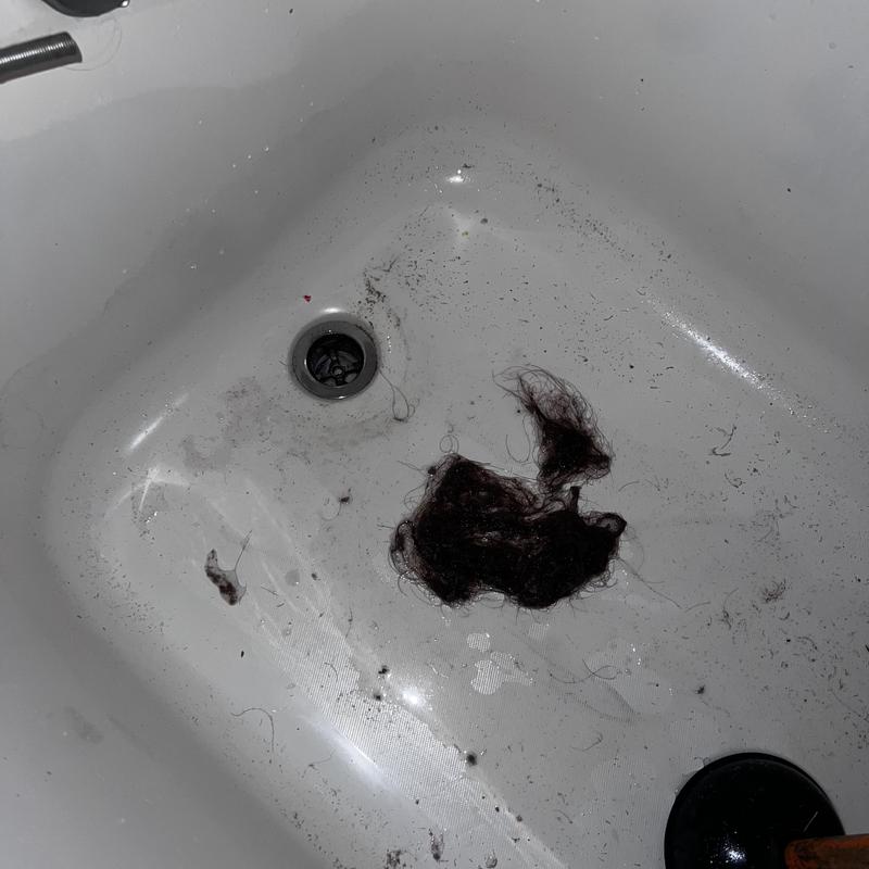 Bathroom drain clogged with hair and debris removal