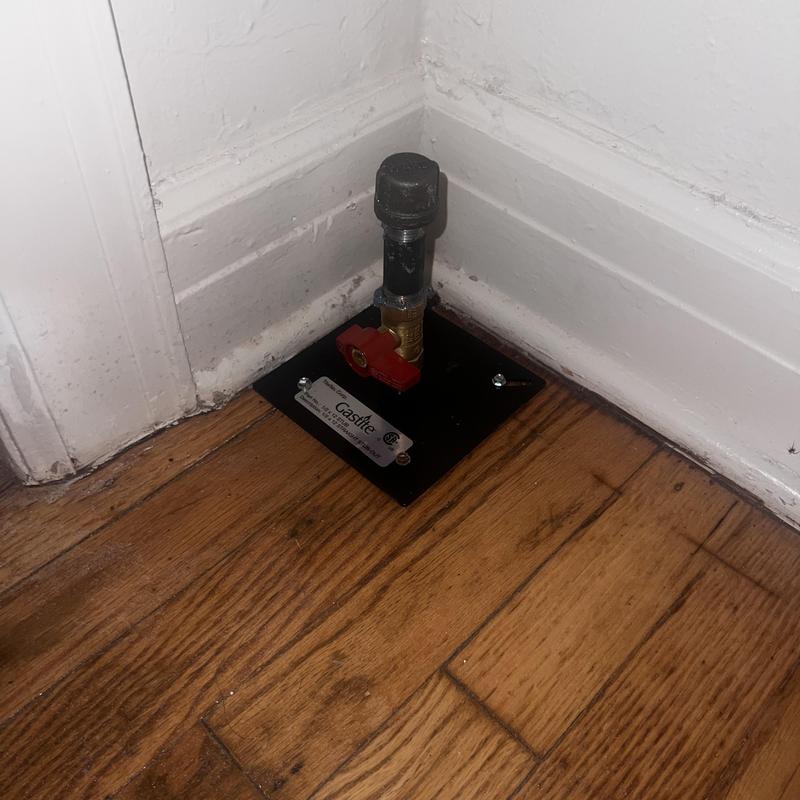 Gas shutoff valve with floor mounting plate on wood floor