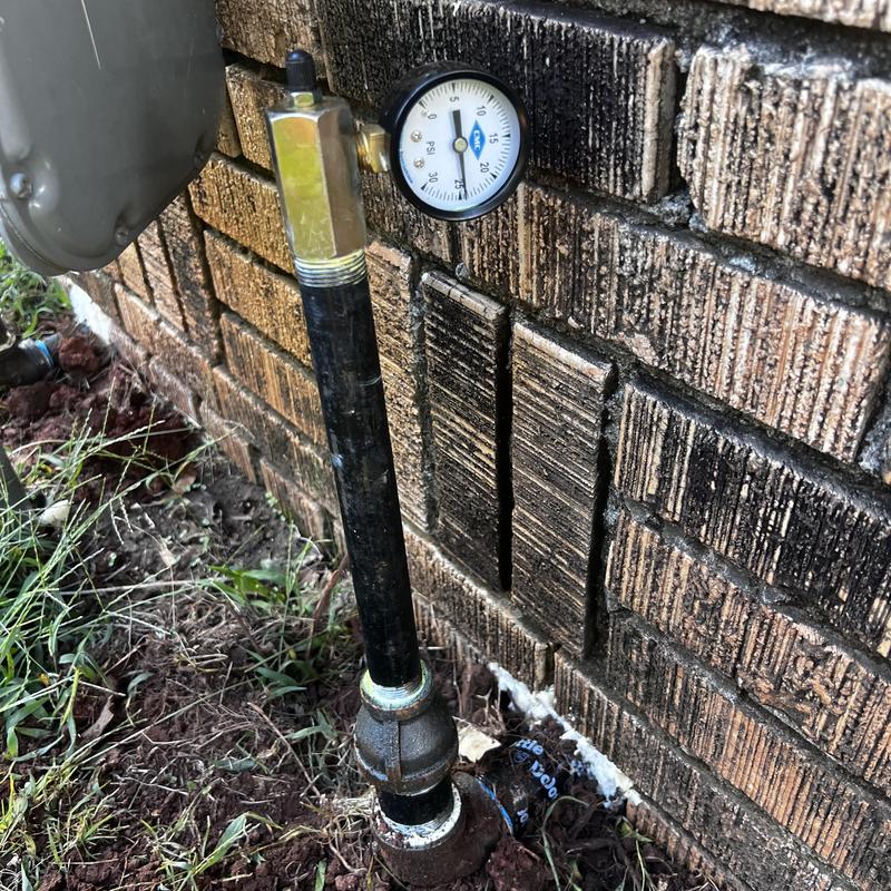 Gas pressure gauge and pipe on brick wall exterior