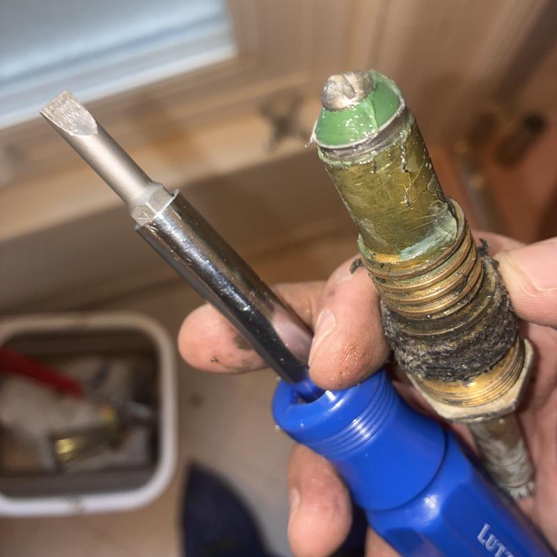 Shower faucet stem and screwdriver held by hand