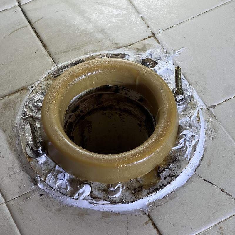 Toilet flange with wax ring and bolts on tiled floor