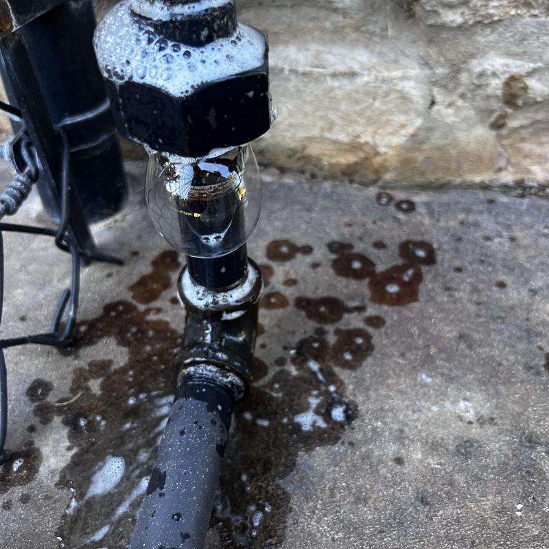 Gas valve with leak bubbles on concrete floor