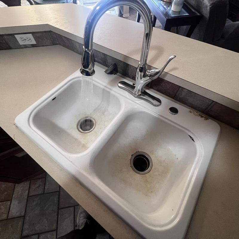 Delta kitchen faucet with running water over sink basin