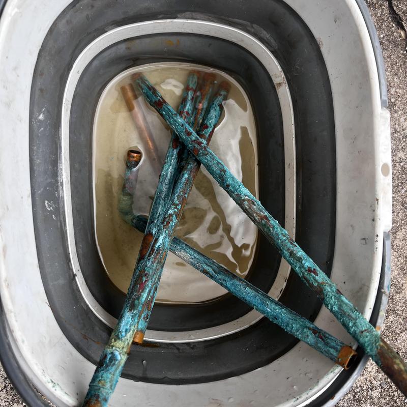 Copper water pipes with corrosion and leaks in tub