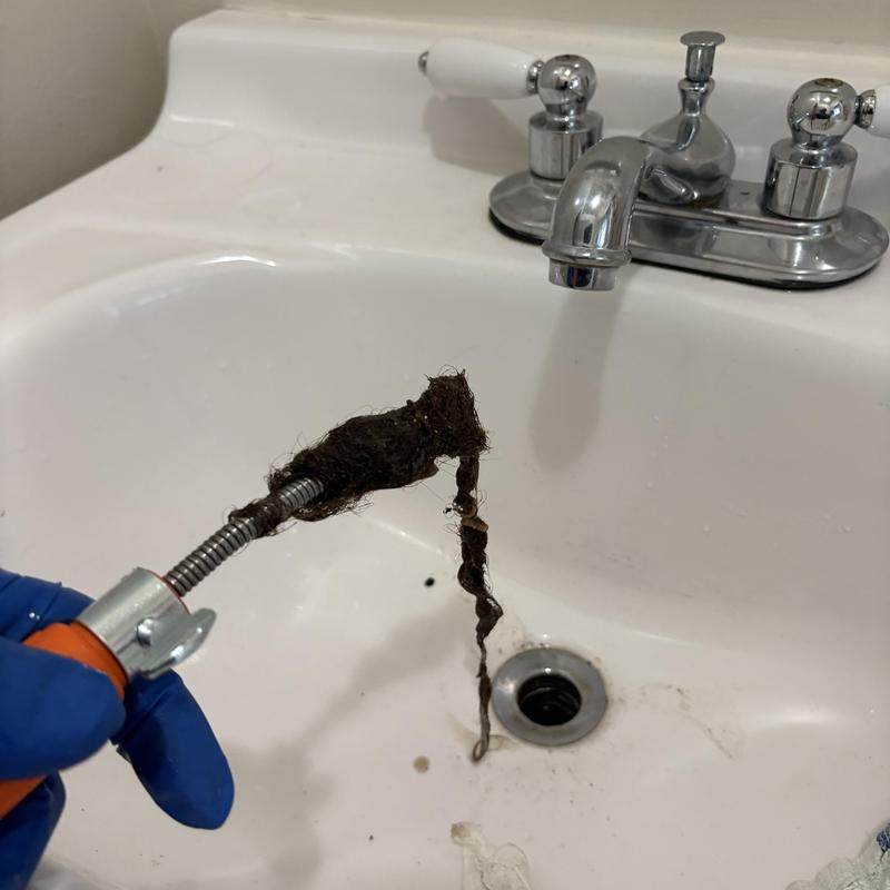 Bathroom sink drain clearing with hair removal cable