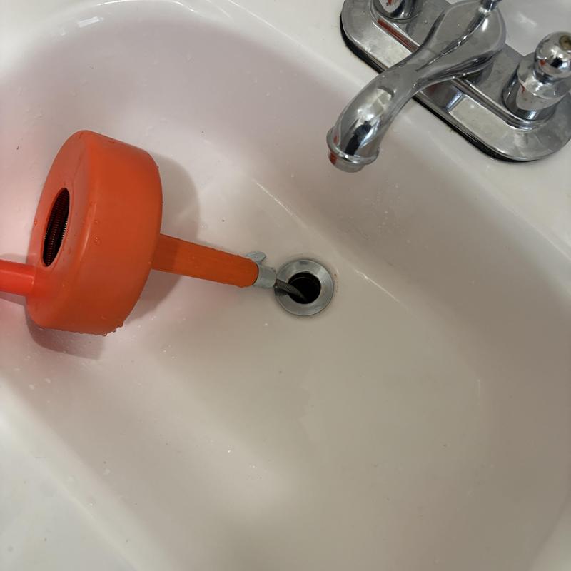 Bathroom sink drain clearing with plumbing snake tool