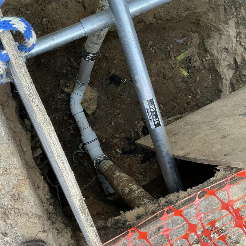 PVC sewer line with new fittings in excavation hole