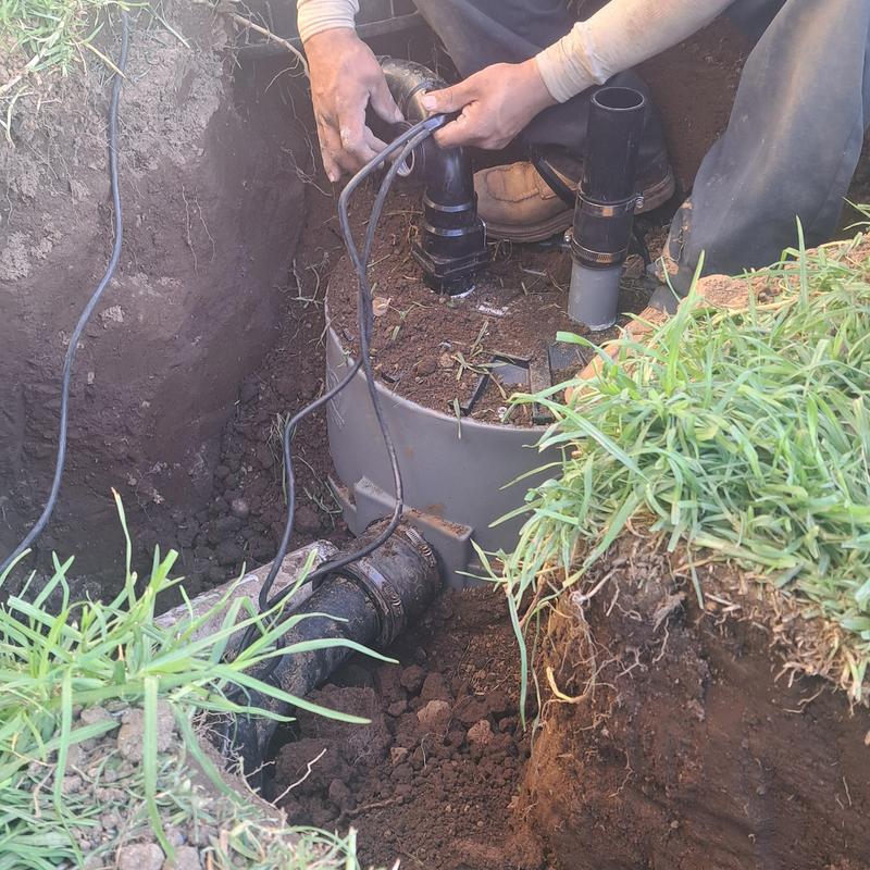 Sewer ejector pump installation in yard trench