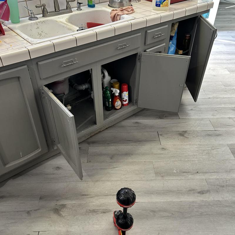 Kitchen sink drain pipes with open cabinet doors