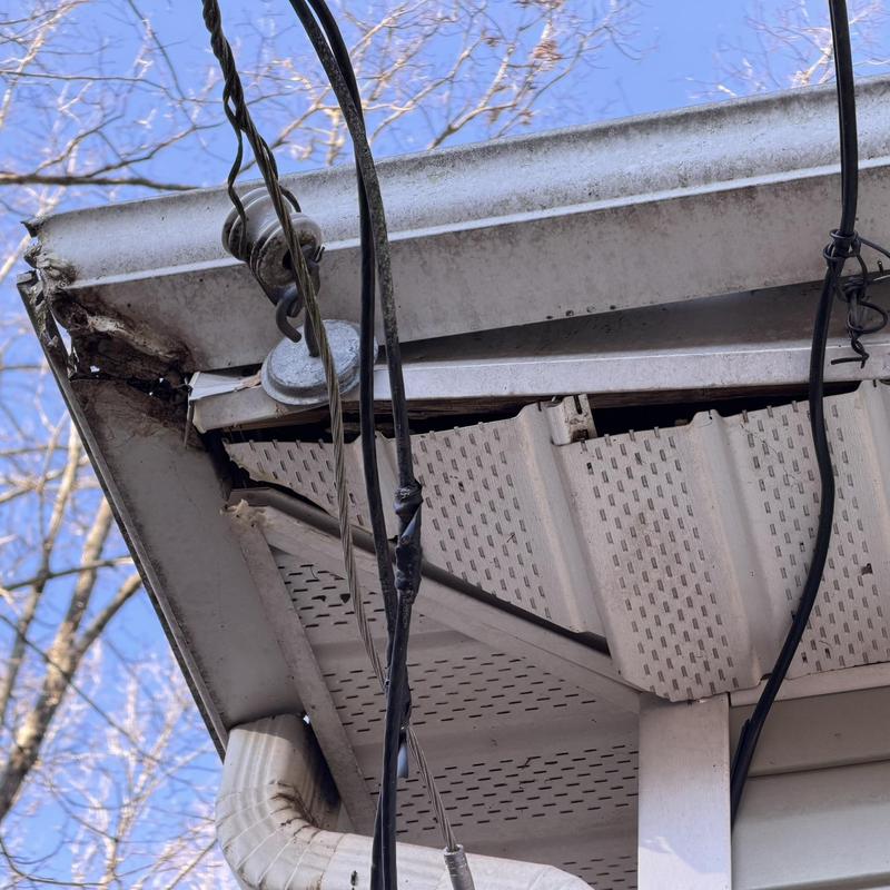 Damaged wood and metal fascia with gutters and wiring