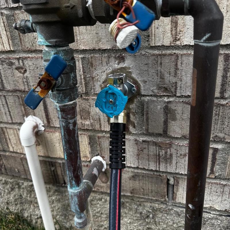 Outdoor hose bib installation with attached hose in brick wall