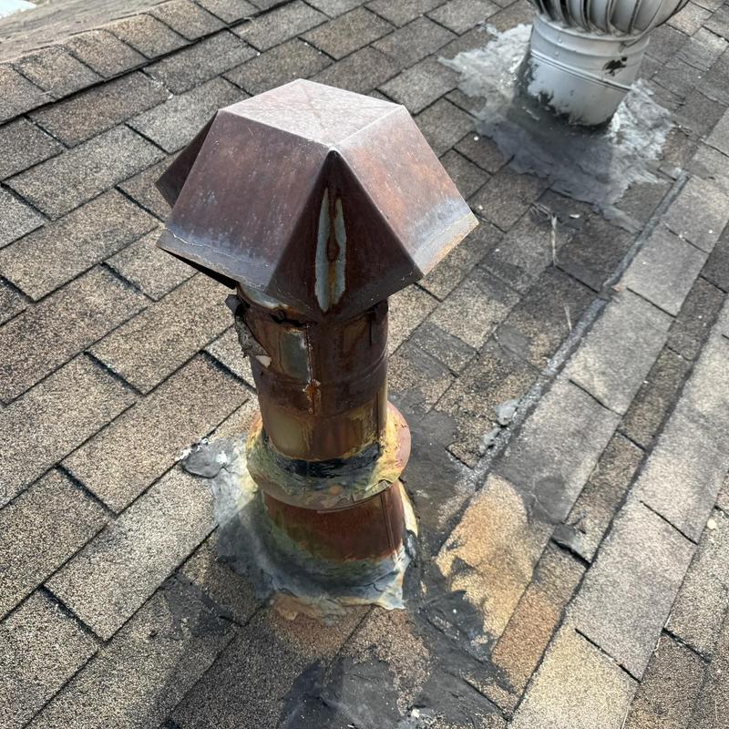 Rusty HVAC vent stack on worn asphalt shingle roof