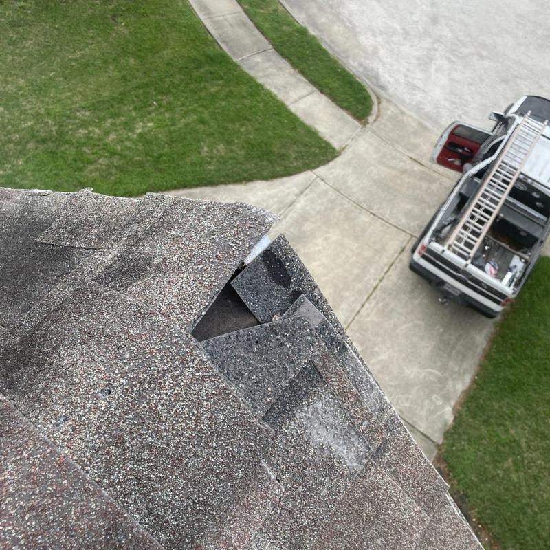 Damaged asphalt roof shingles with lifted corners