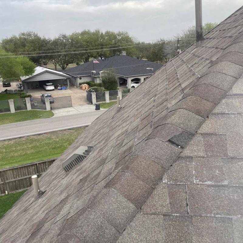 Asphalt roof shingles with wind damage and missing pieces