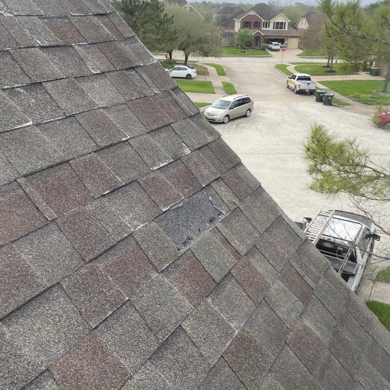 Asphalt roof shingles with storm damage on residential roof
