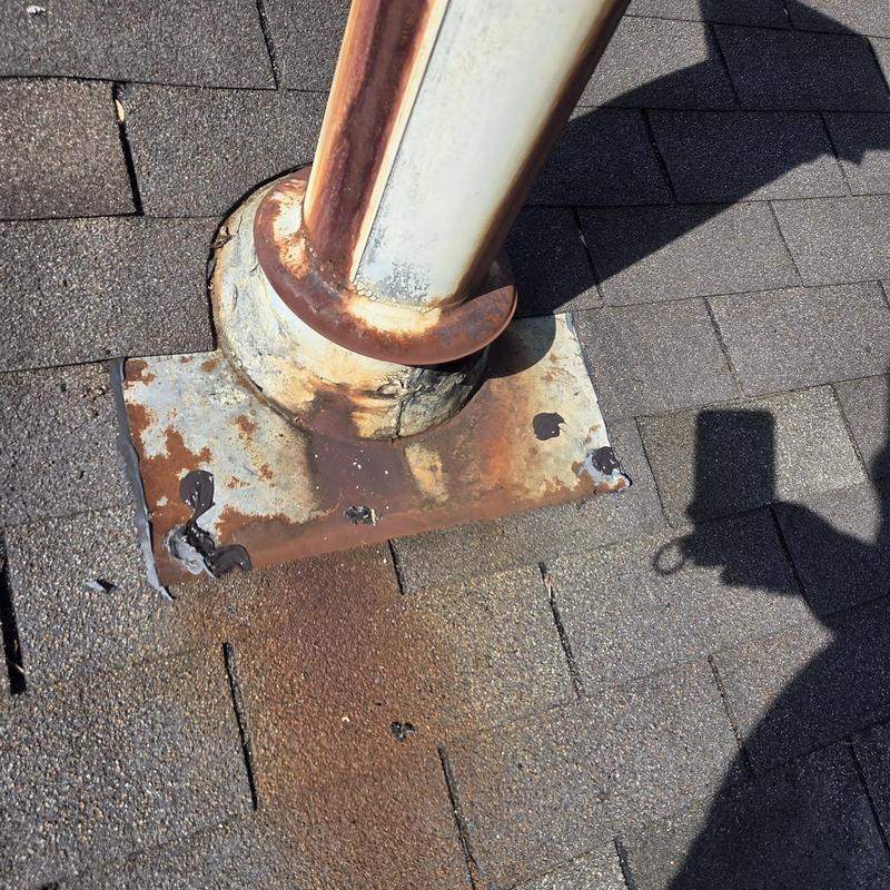 Roof vent pipe with rusted metal flashing on shingles