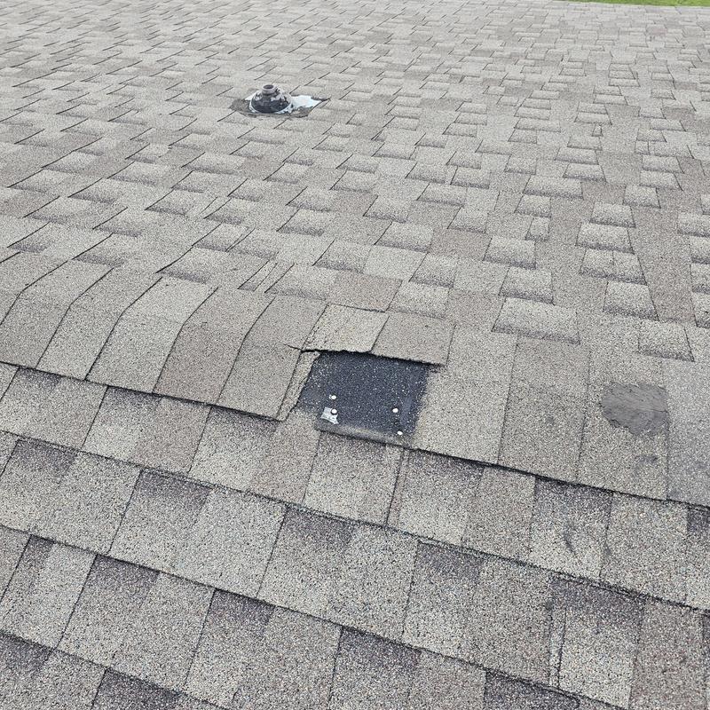 Roof shingles with hail damage and missing shingle section