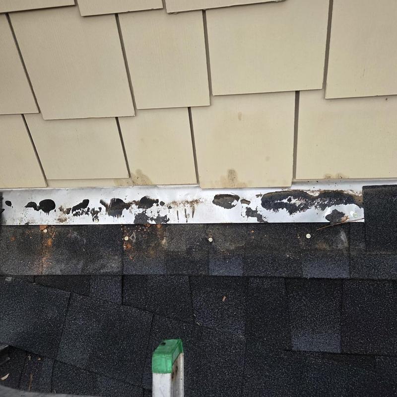 Shingle roof with damaged flashing near siding panels