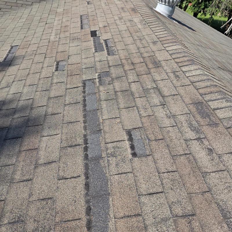 Asphalt shingles with hail and wind damage on roof