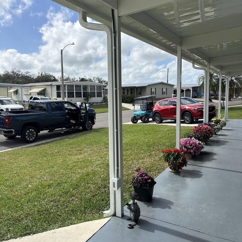 Custom white pergola with flower pots along porch